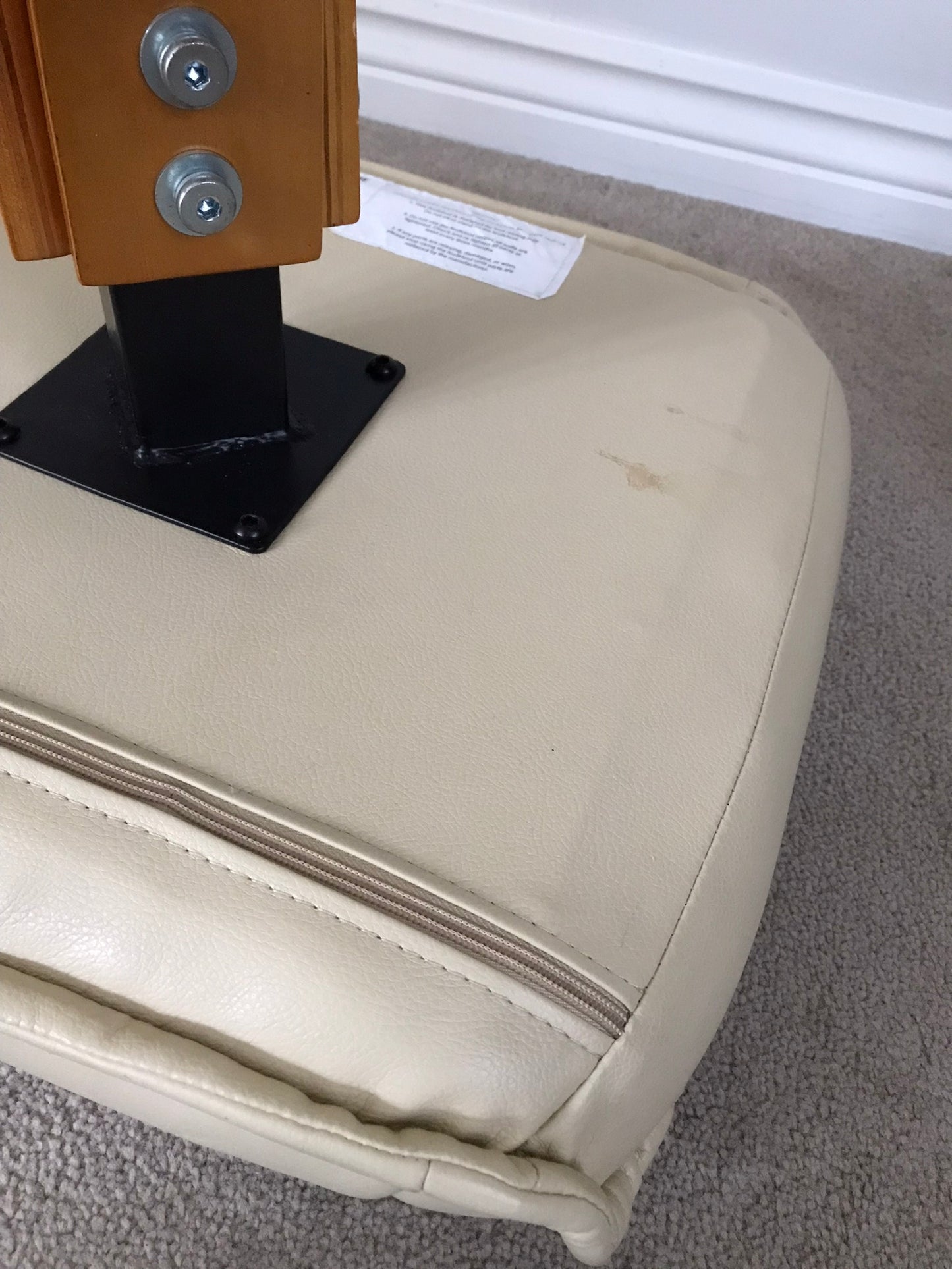 Cream faux leather footstool with wooden legs to match recliner chair.