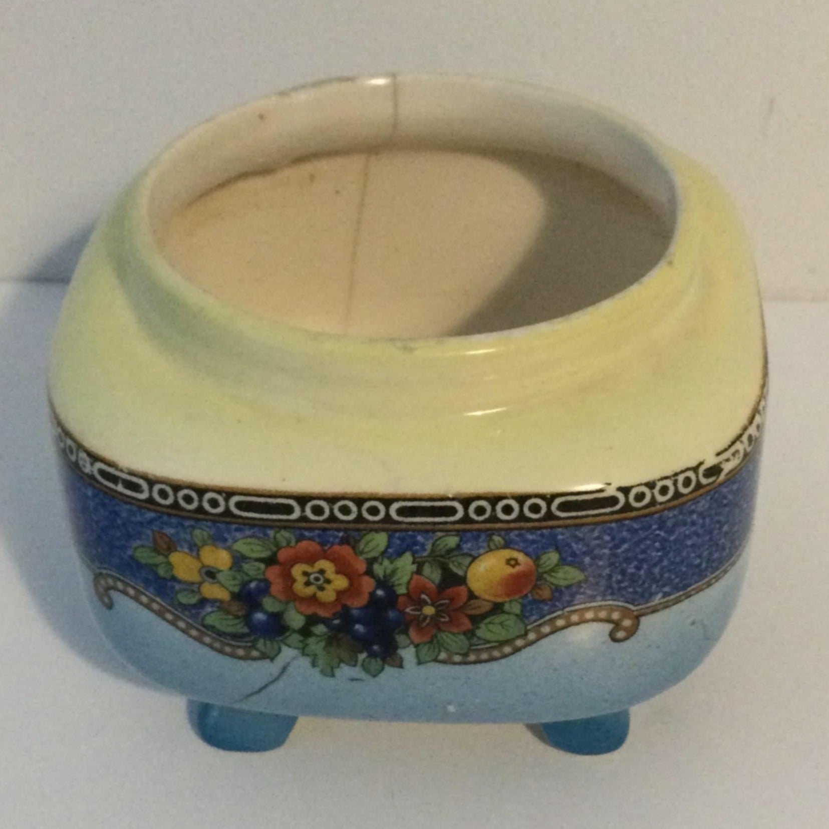 A vintage porcelain sugar bowl with blue floral design on a footed base with gold accents.