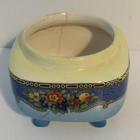 A vintage porcelain sugar bowl with blue floral design on a footed base with gold accents.